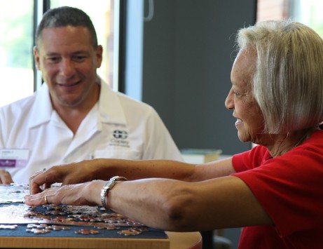 senior doing puzzle with senior living employee