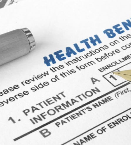 Health benefit example form being filled out by silver pen